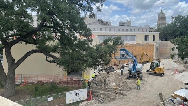 Construction trucks outside future education center with San Antonio skyline in background