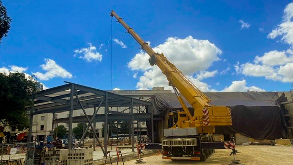 Large yellow crane outside construction of Alamo Education Center