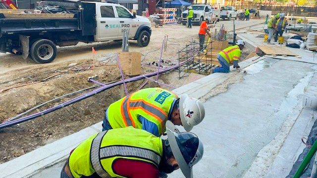 Two construction workers smoothing concrete on a walkway