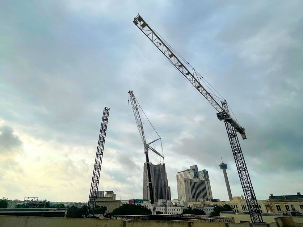 Three large cranes over San Antonio cityspace skyline