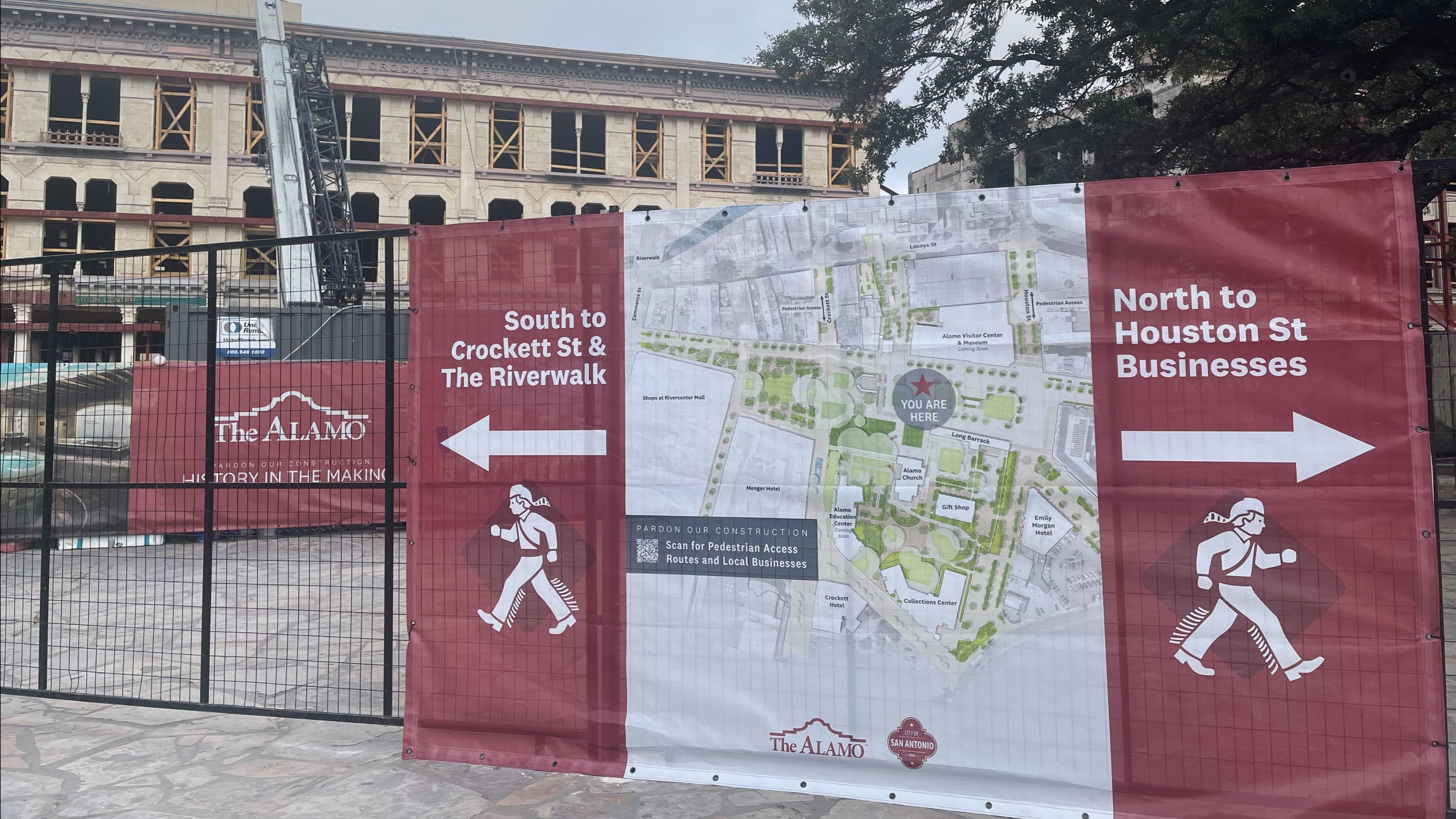 Alamo wayfinding signage with arrows on each side and a map in the middle wrapped on a construction fence