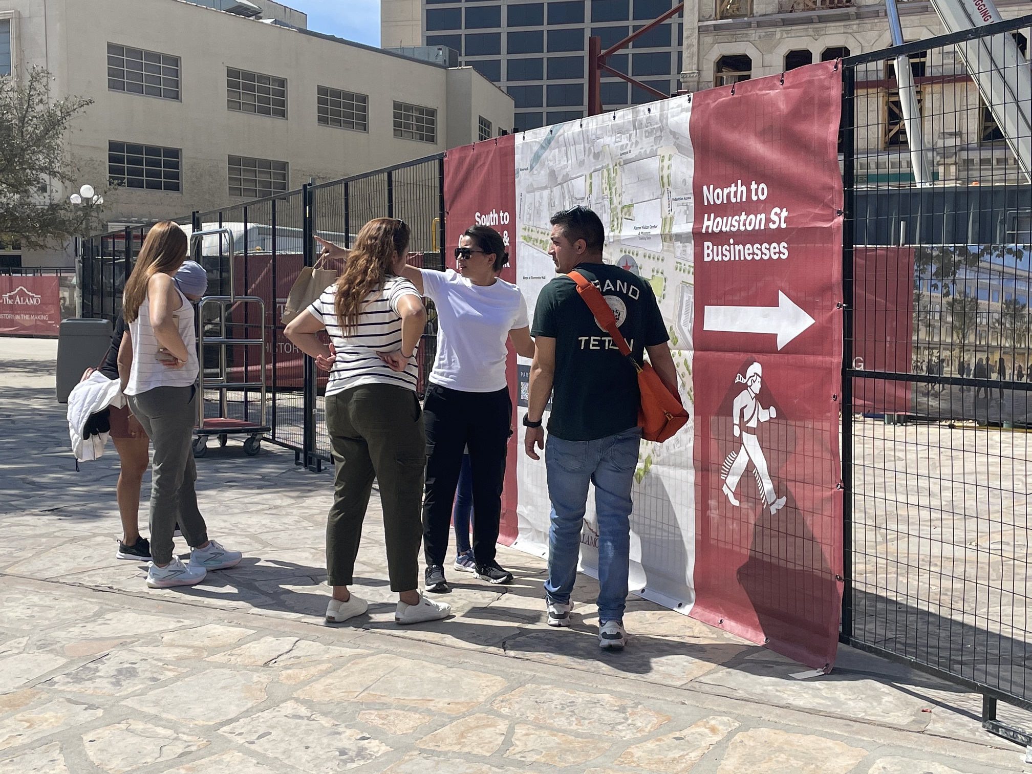Visitors standing in front of a construction fence wrapped with wayfinding signage