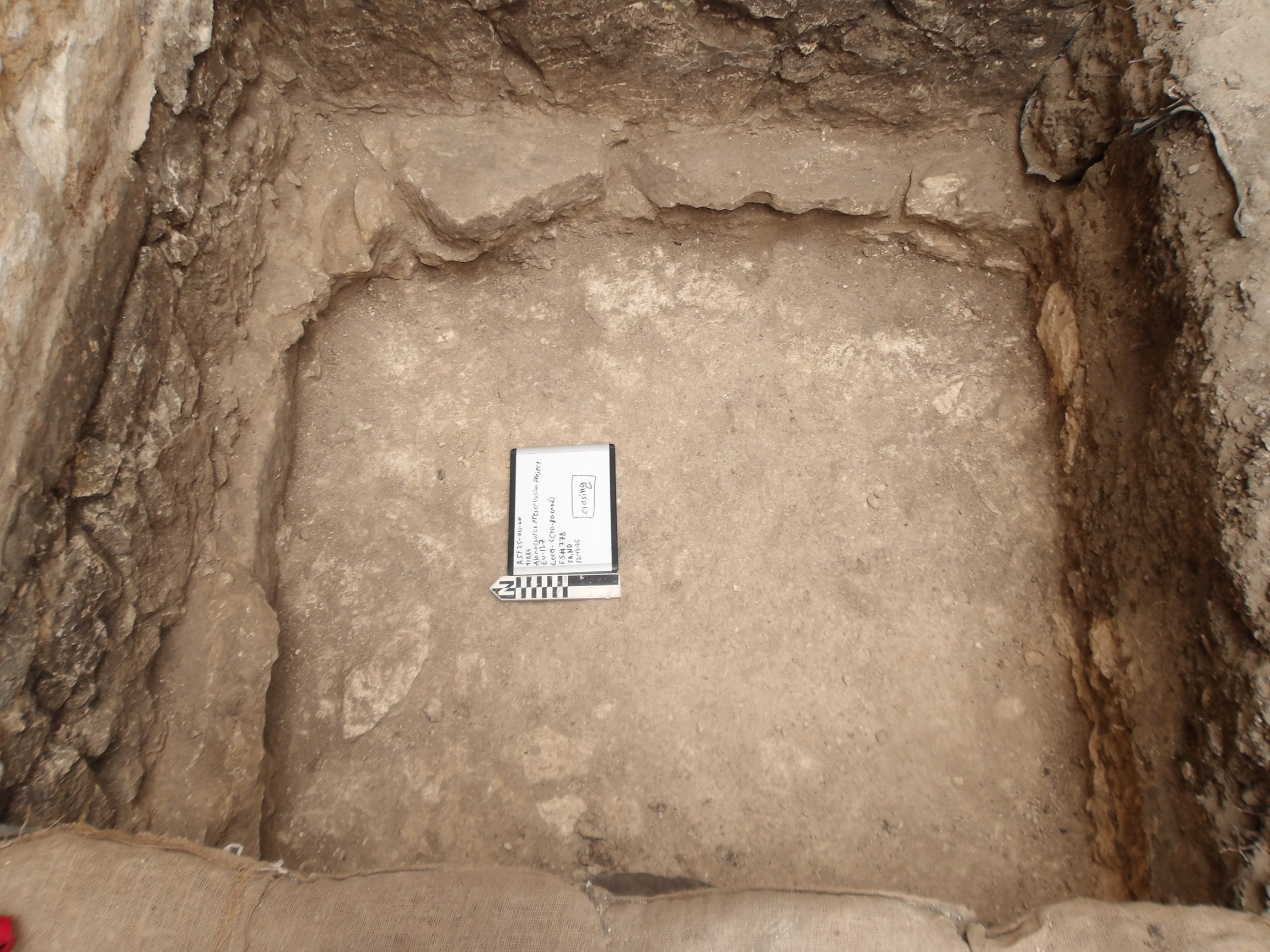 Bottom of excavation unit with stone border along wall