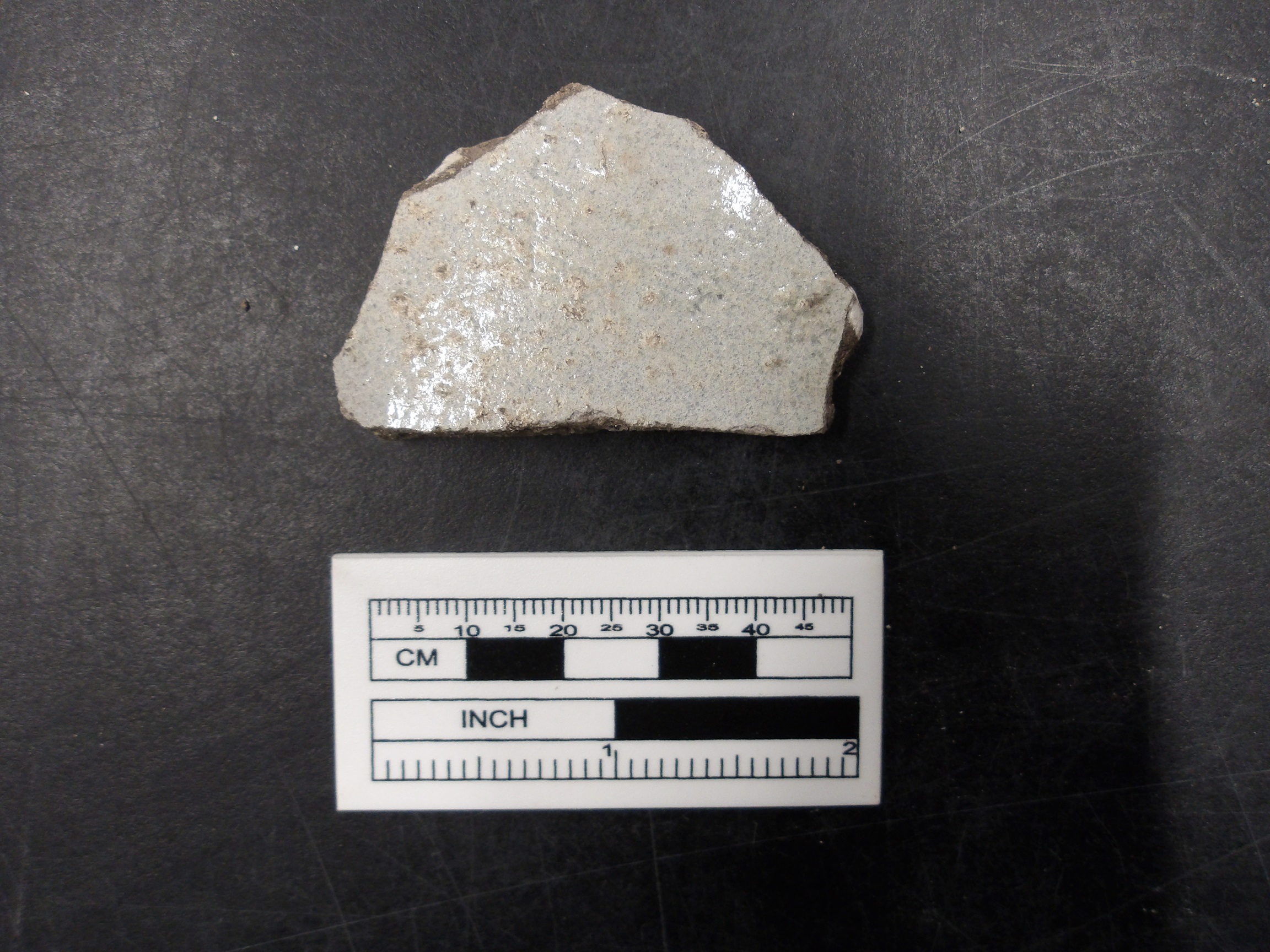 Salt glazed stoneware fragment next to a ruler for size
