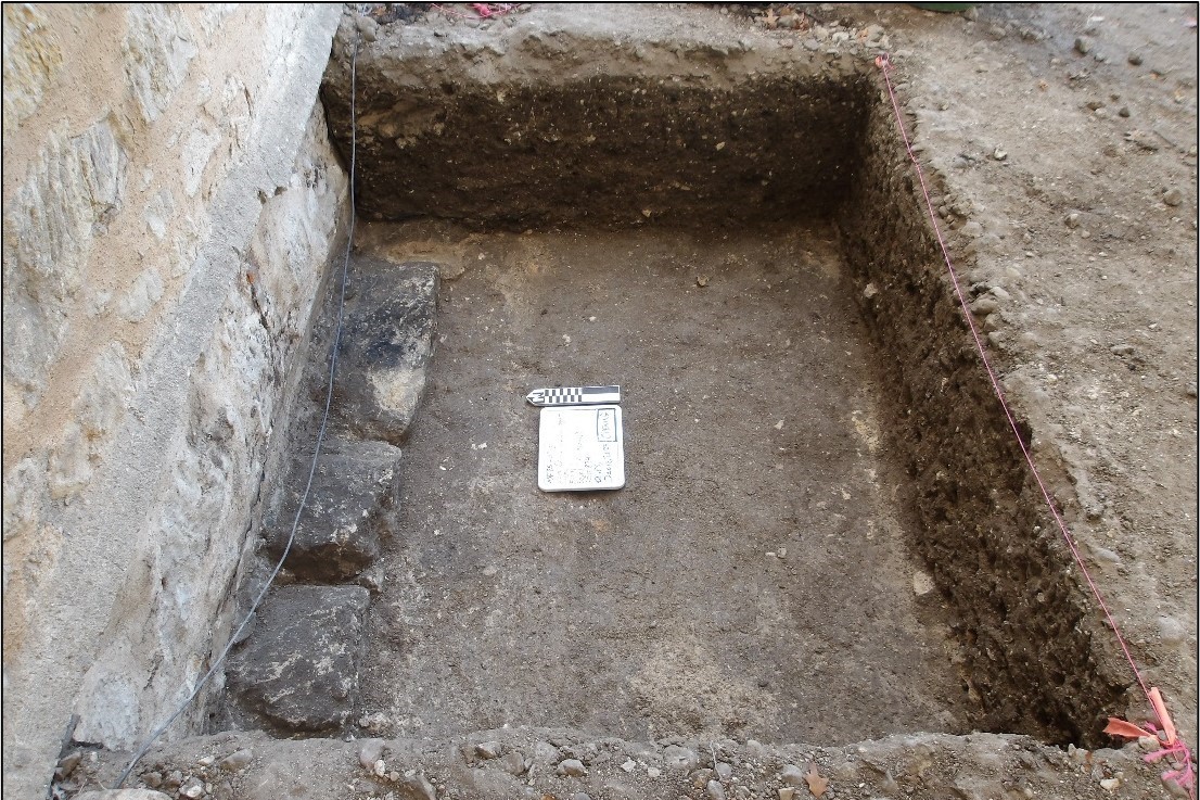 Three black stones inside the perimeter of an excavation unit