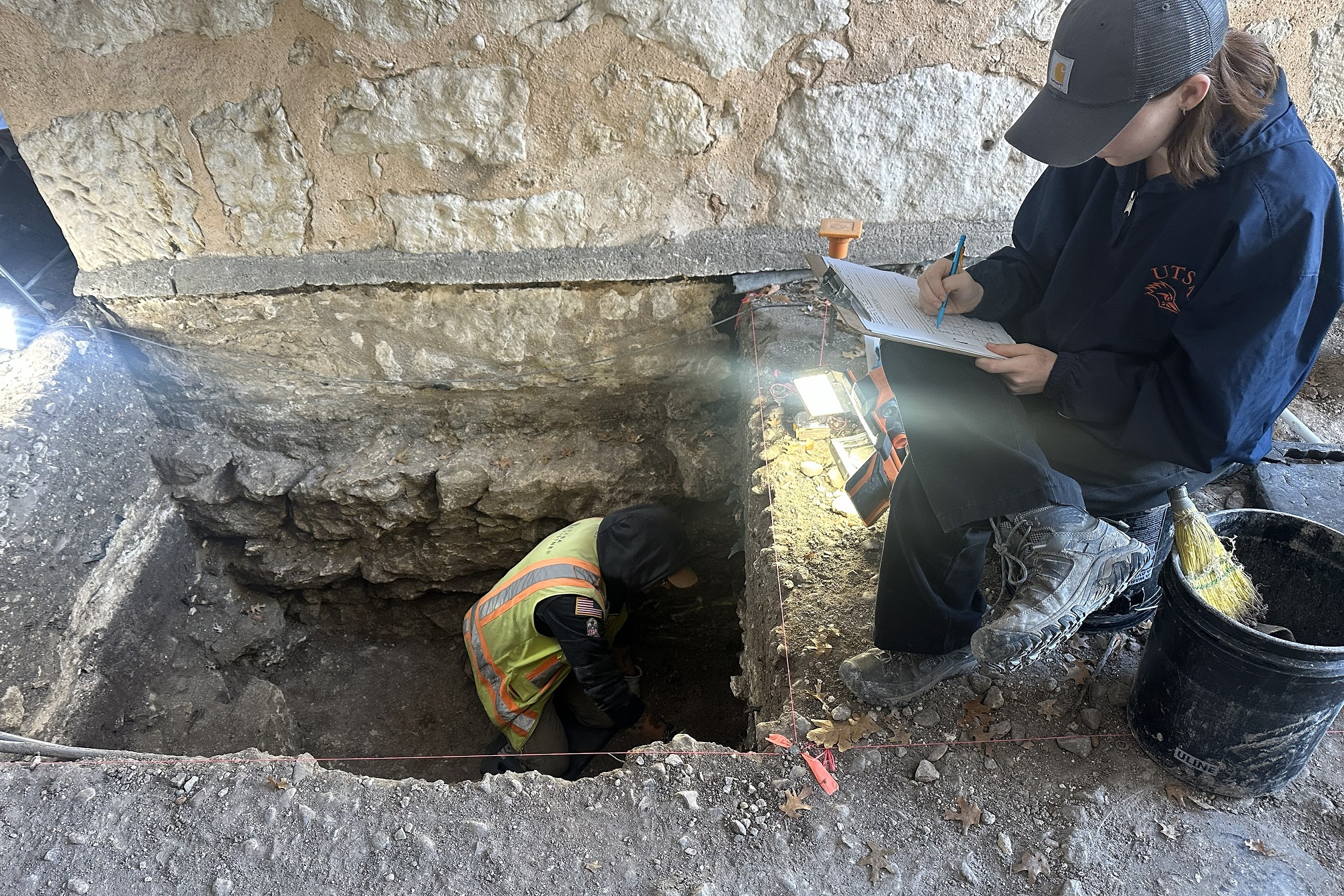 Archaeologist completing paperwork at top of excavation unit