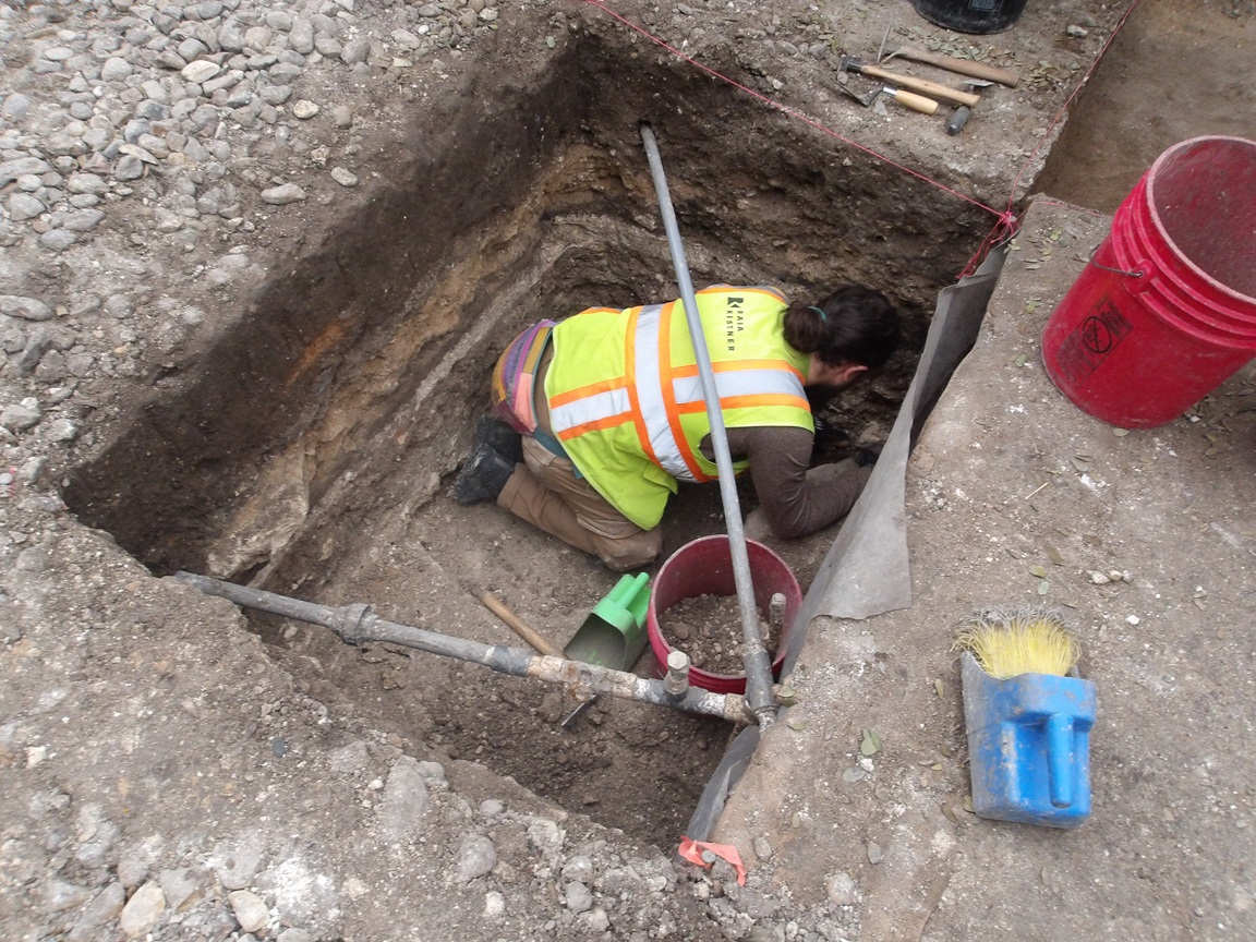 Archaeologist inside an excavation unit digging at surface