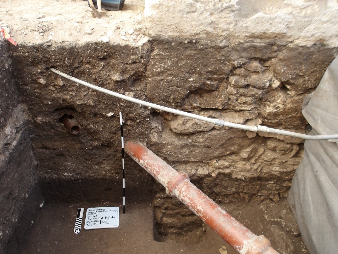 Limestone wall of an excavation unit with a pipe across the bottom