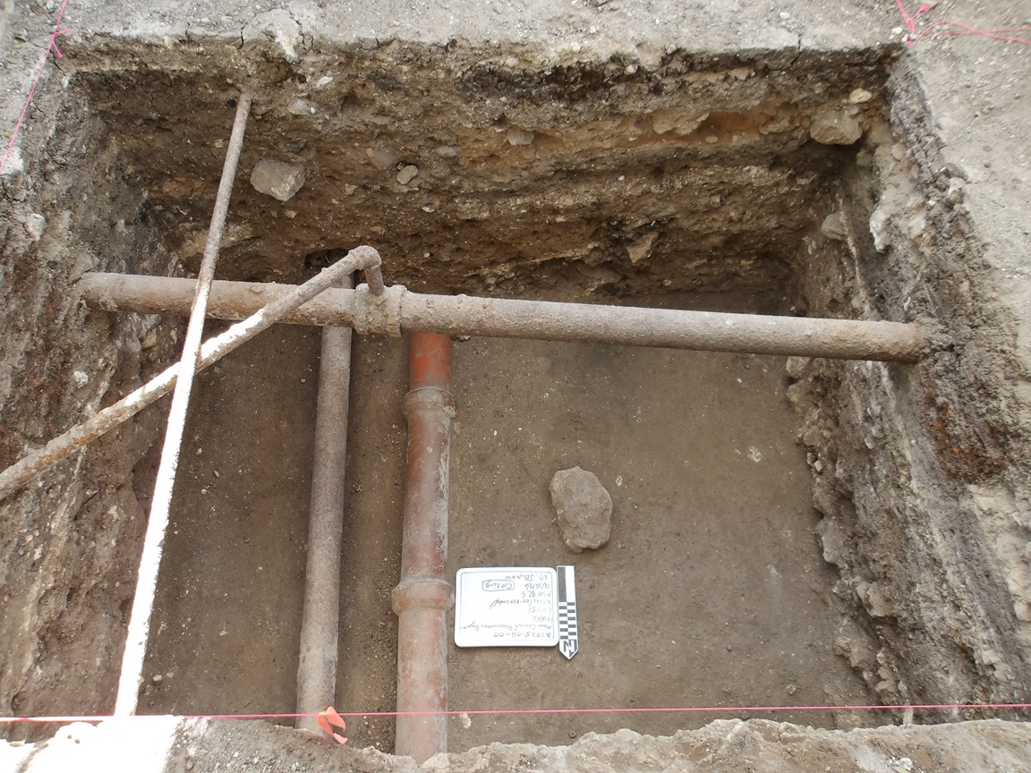 Inside an excavation unit 100 cm below surface with crossing utility pipes