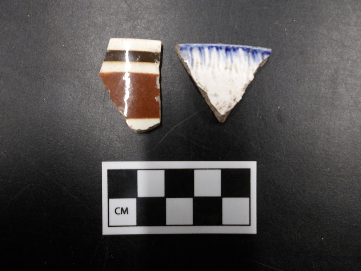 Ceramic pieces on a black background next to a ruler for size