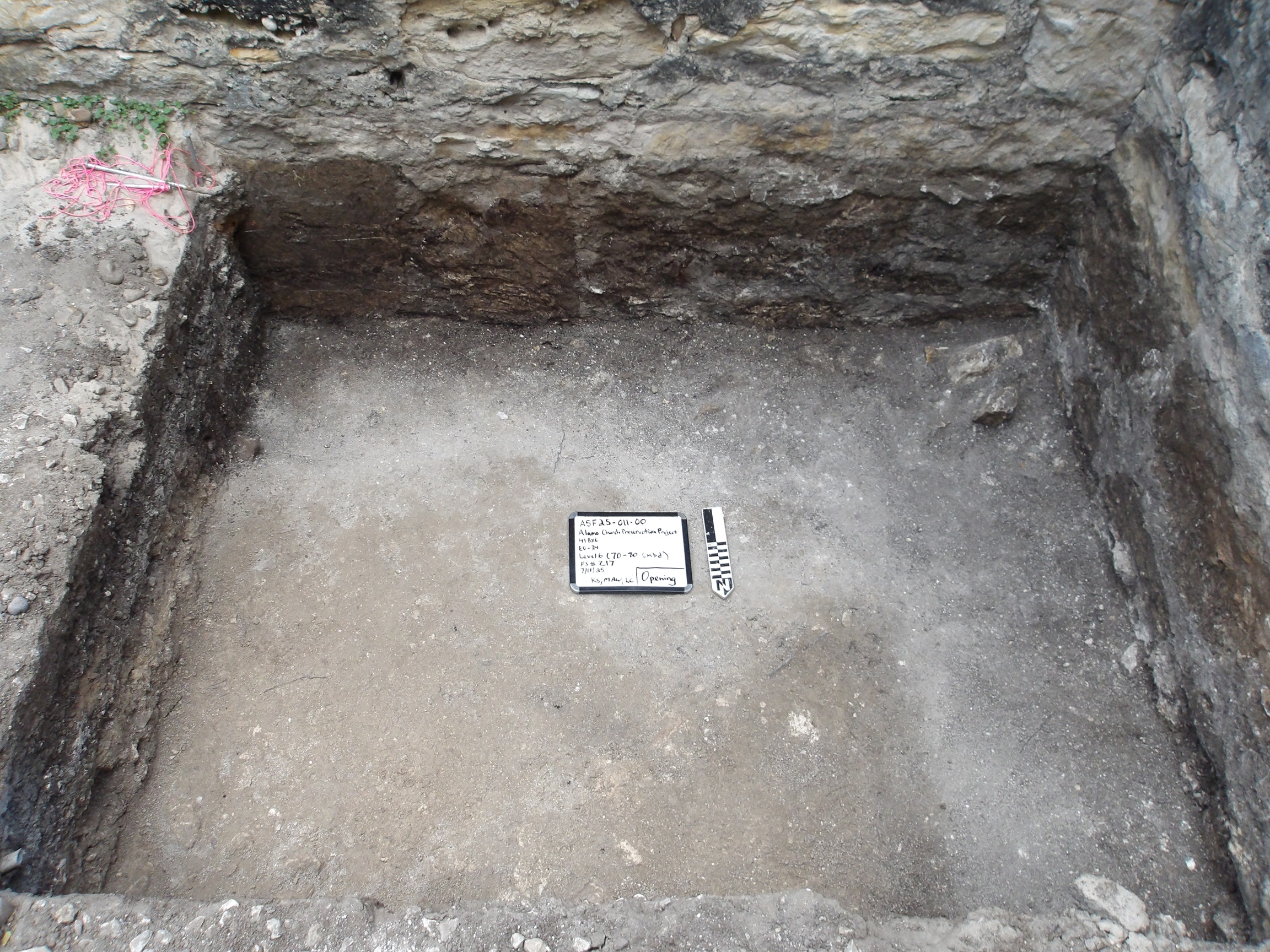 Square area inside an excavation unit with a whiteboard and marker in the center