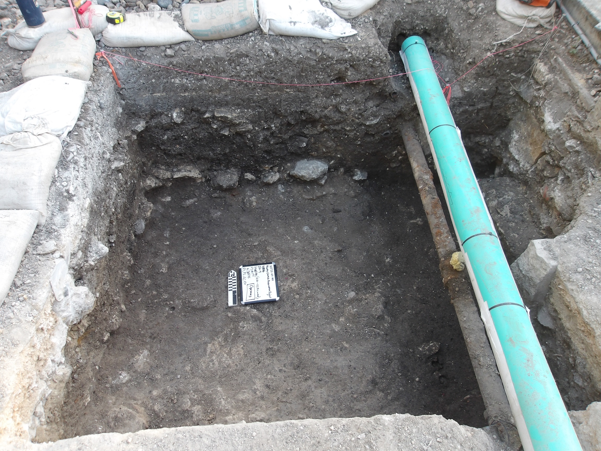 Inside of an excavation unit with a green pipe along one side of the border