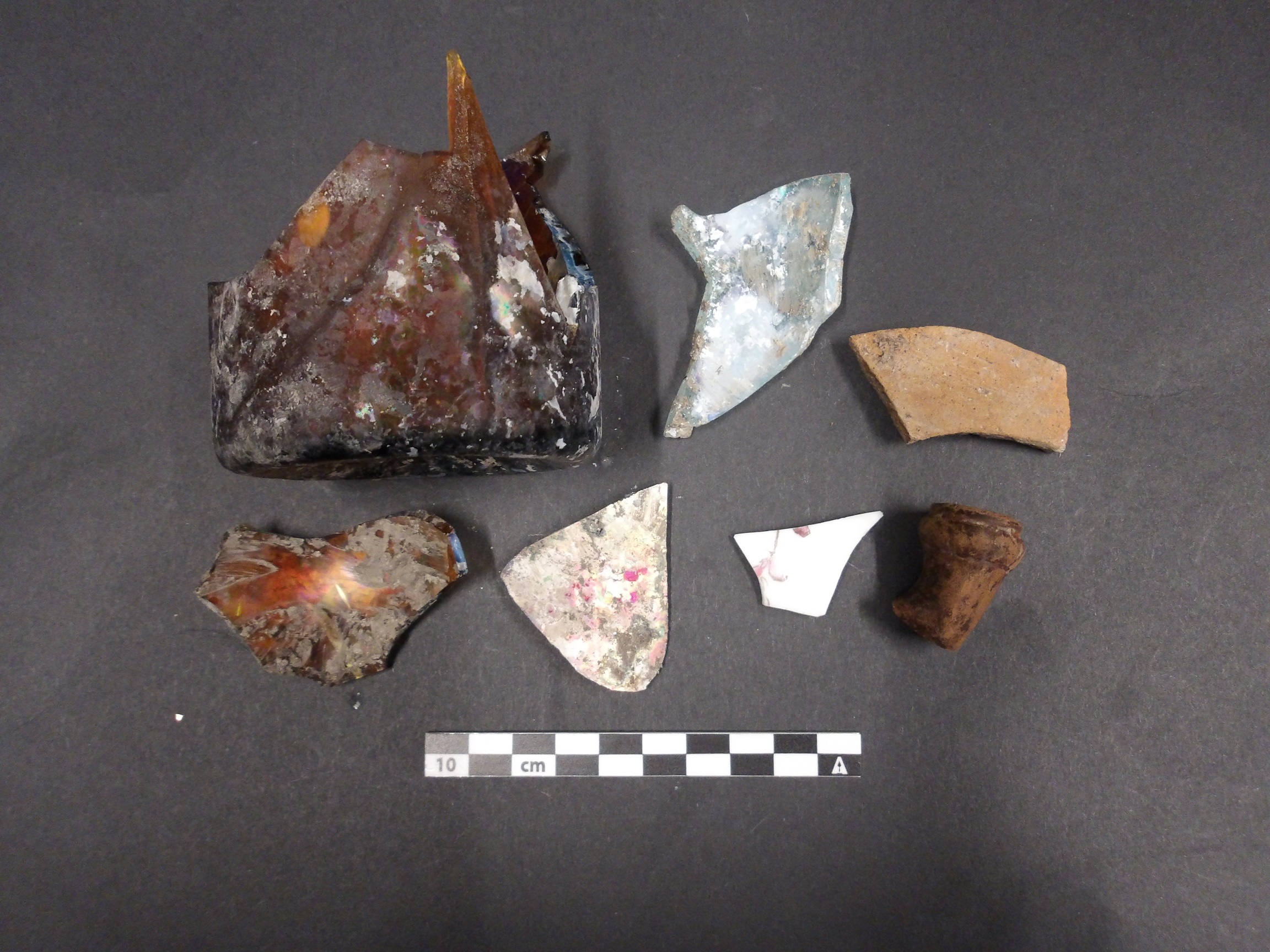 Artifacts from an excavation unit with ceramics, glass, and a small jar