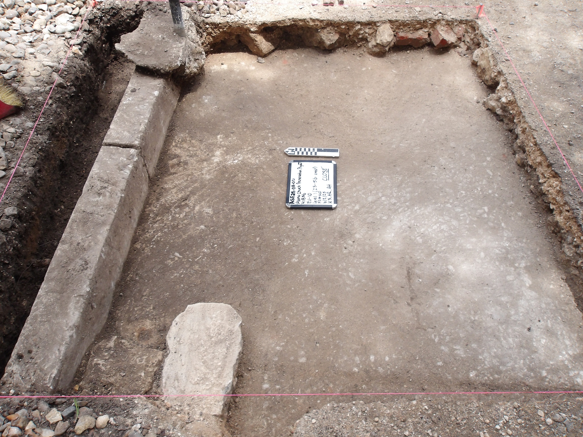 Concrete slab curb at perimeter of excavation unit