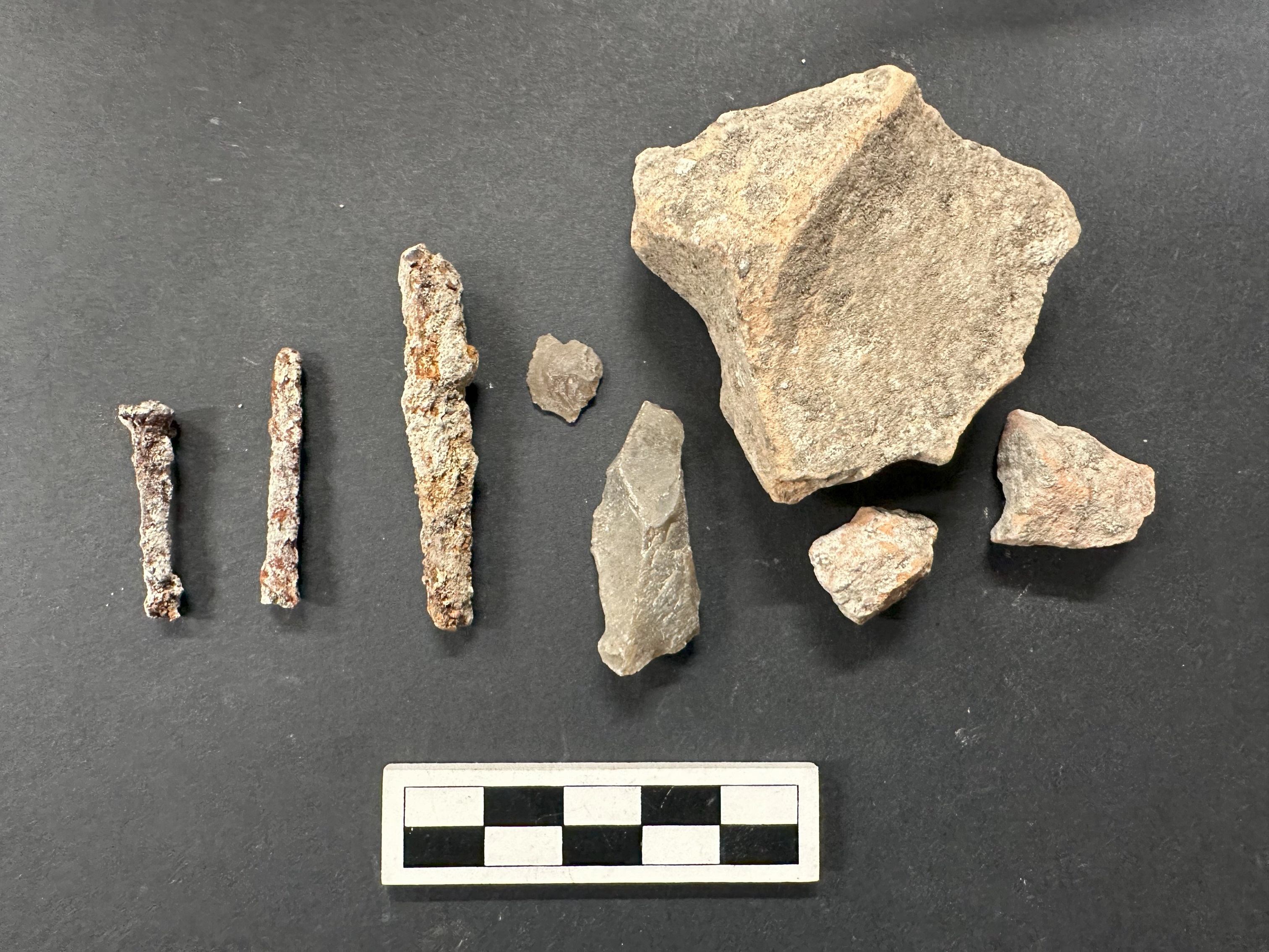 Nail and brick fragment artifacts next to a ruler for size