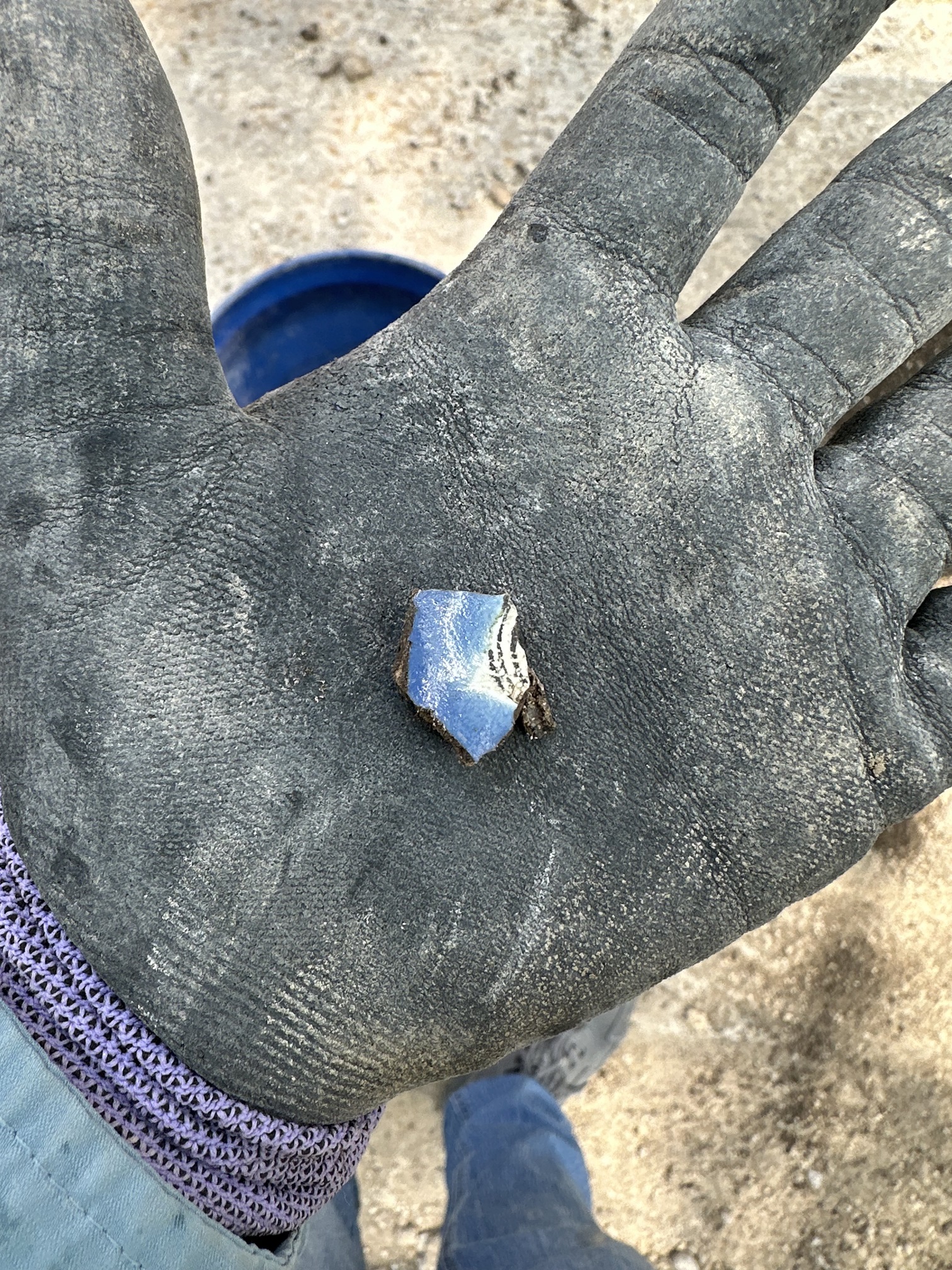 Blue puebla fragment in the palm of a gloved hand