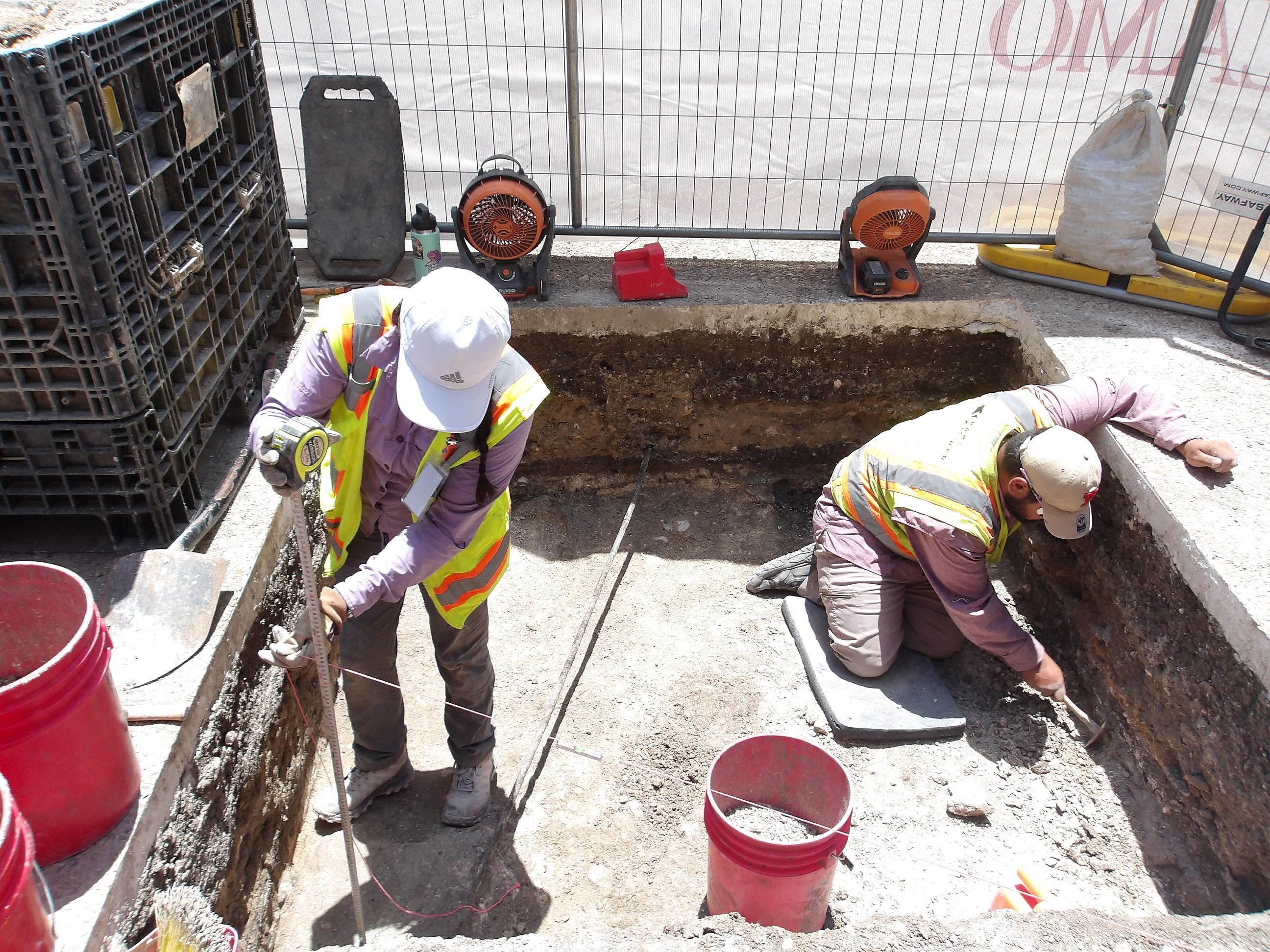 Two archaeologists working inside an excavation unit
