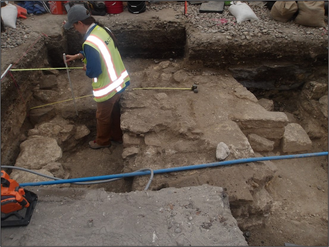 Archaeologist mapping limestone foundation inside an excavation unit