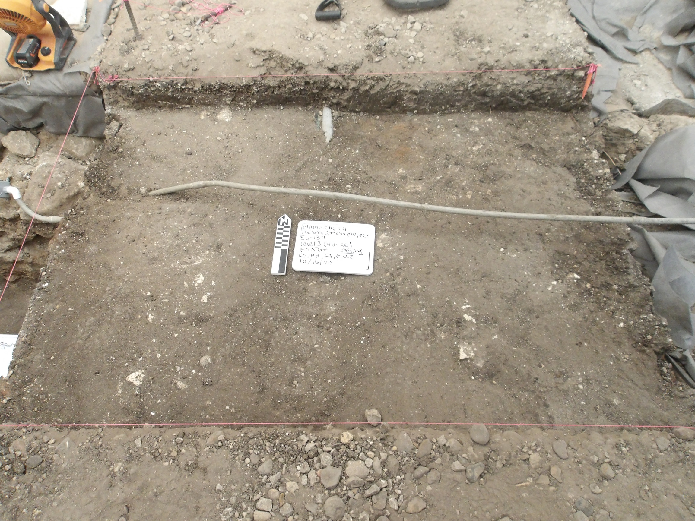 Flat dirt bottom in an excavation unit with a thin pipe over the top