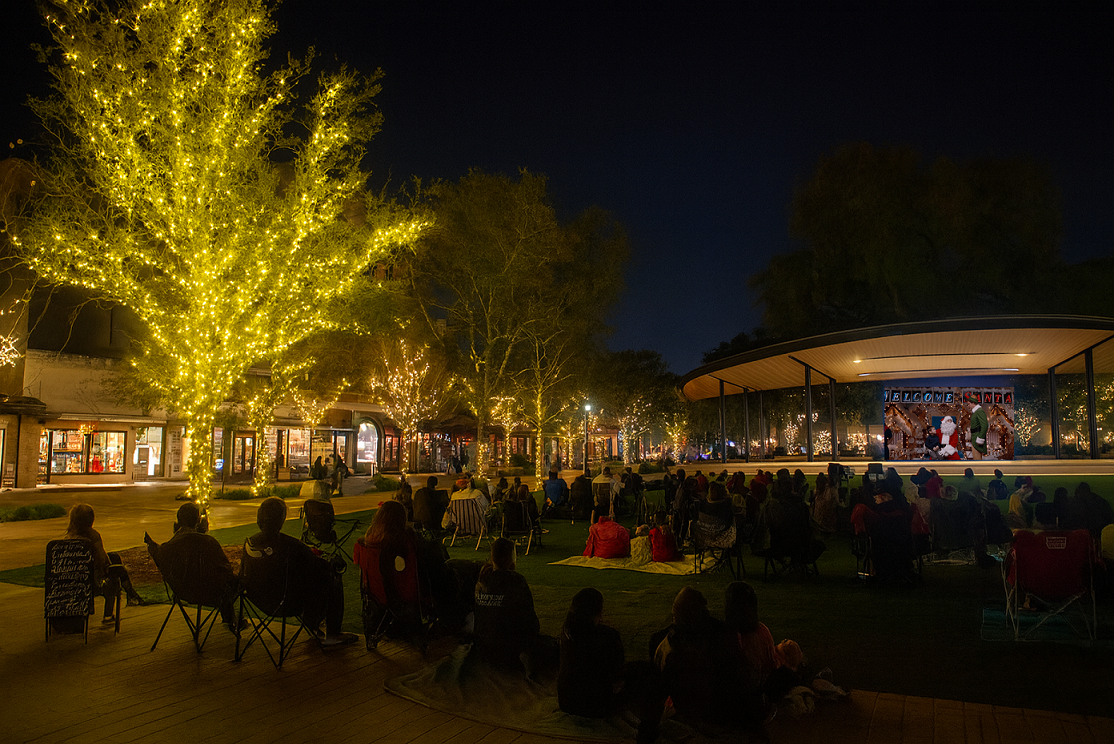 Evening scene with people in chairs and on blankets watching a movie in Plaza de Valero community park